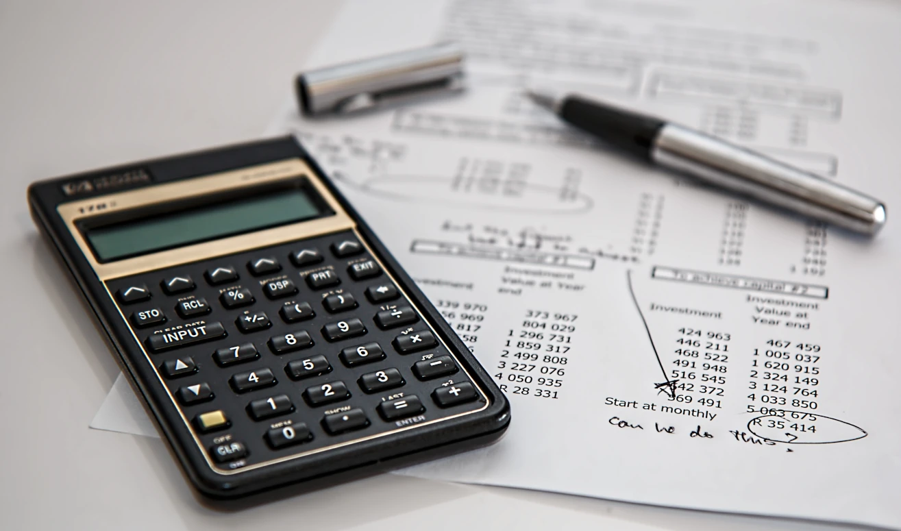 A calculator and a pen standing on a bill