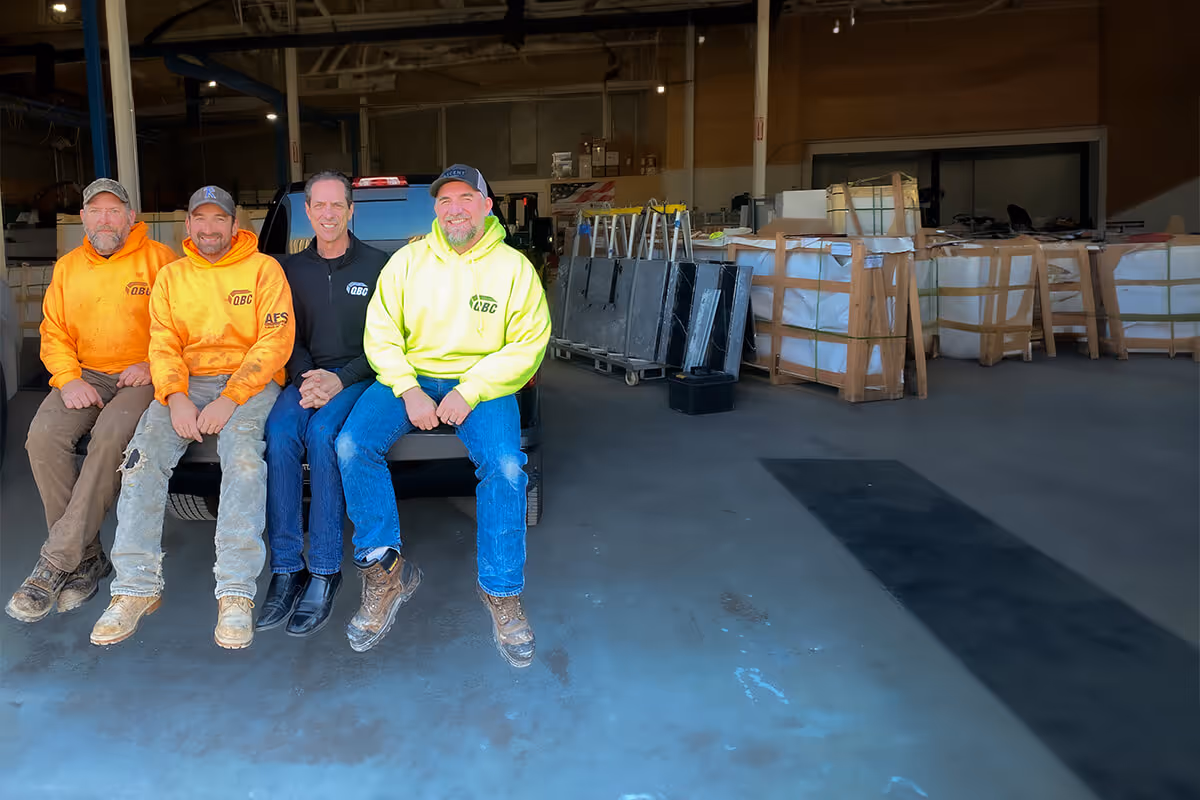 Owners Brian Statz, Kurt Wagner, Brian Keller, and Matt Uebersetzig sitting on the tailgate of a truck in QBC's stone fabrication shop.