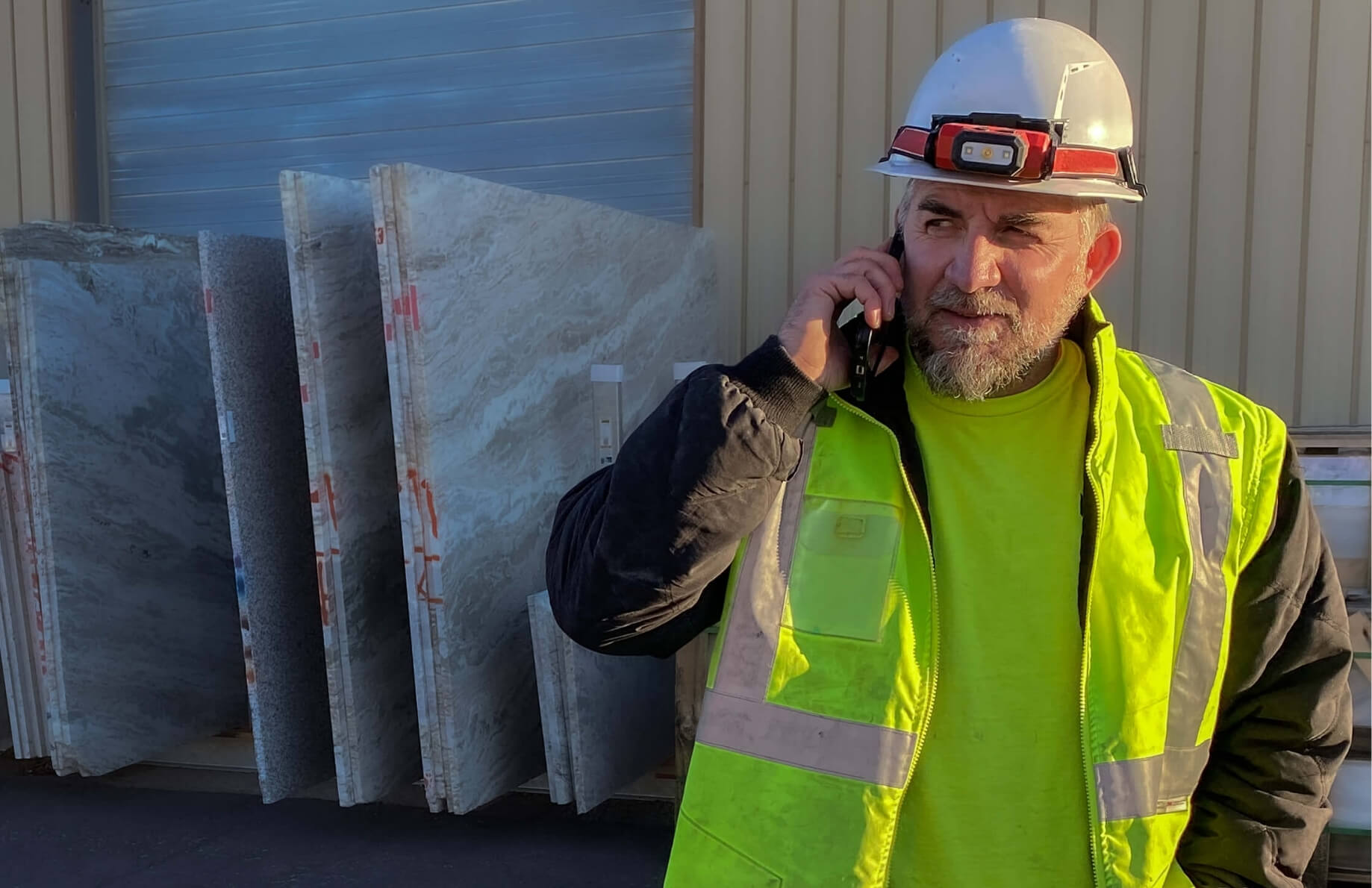 Matt Uebersetzig, owner/founder, on his cell phone with quartz slabs in background.