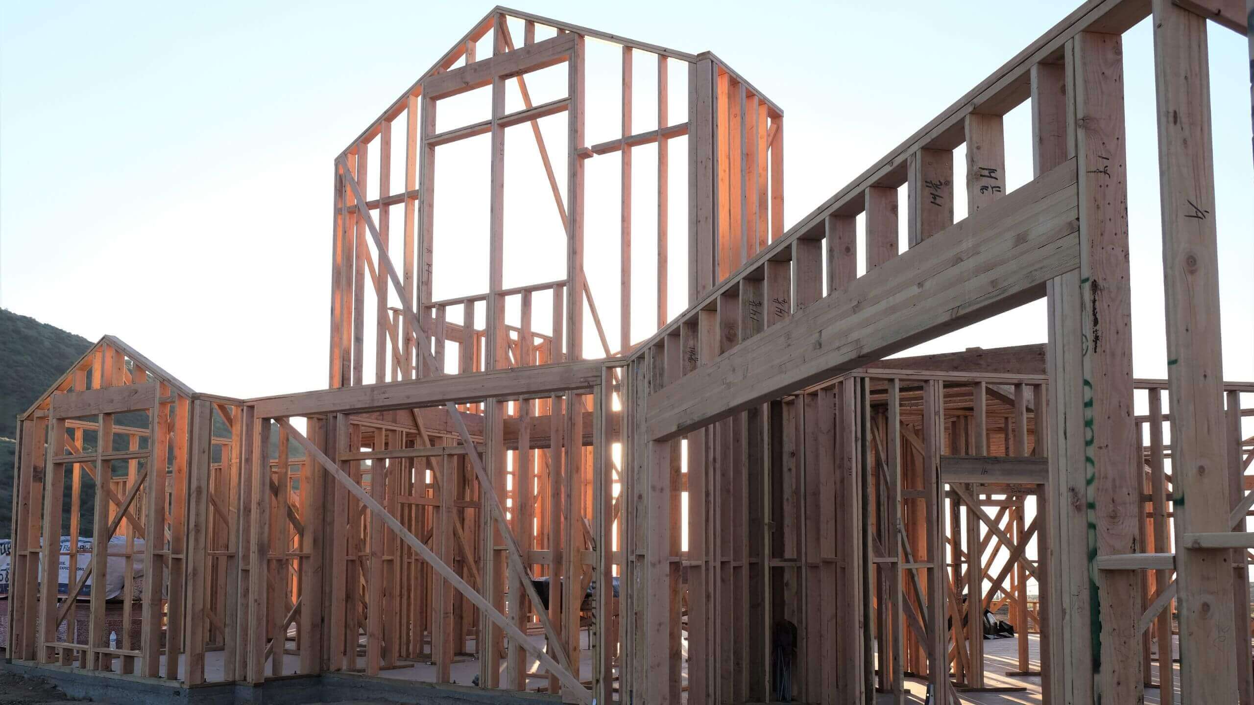 Roof truss and wall framing viewed from below against a blue sky