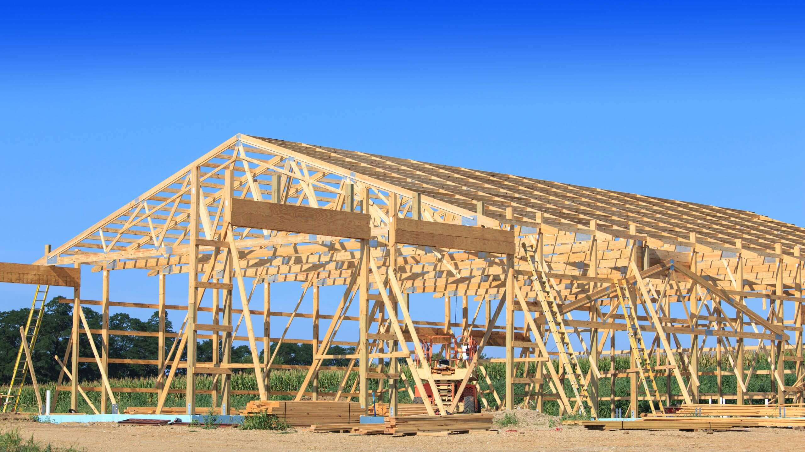 Post-frame barn with roof trusses set against a clear sky