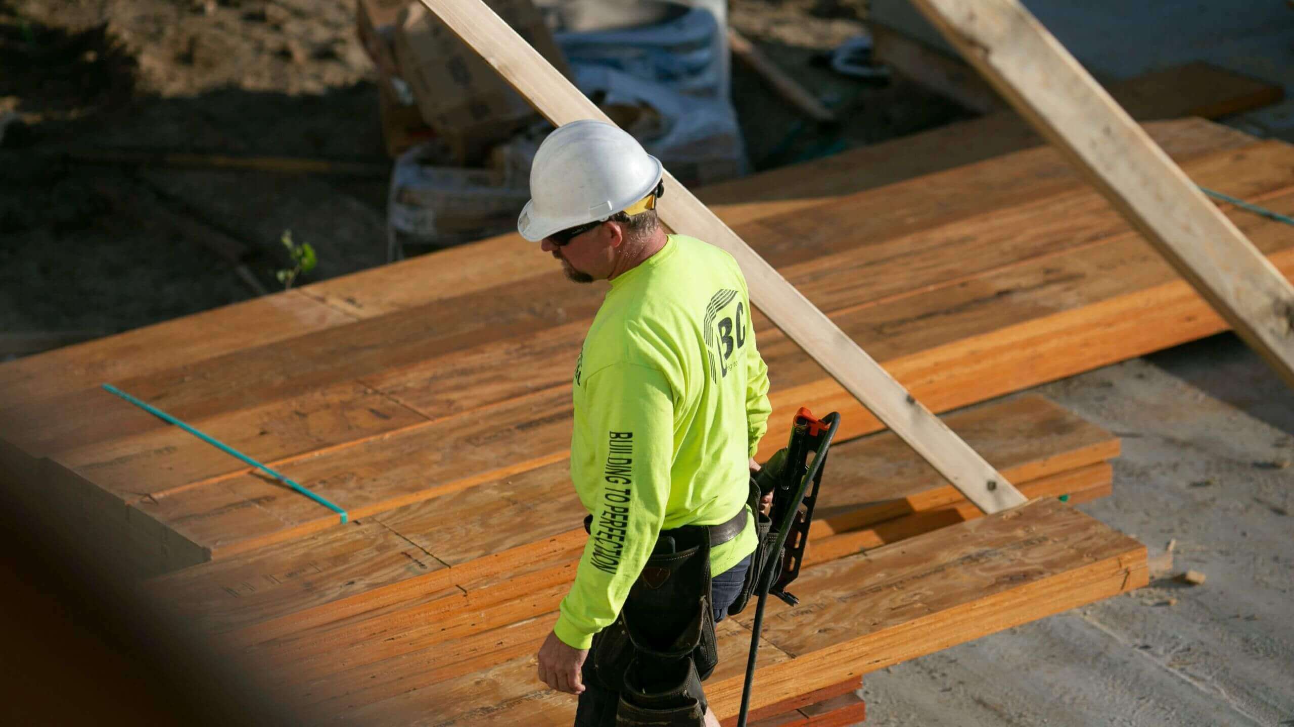 QBC founder framing on a jobsite with a framing nailer and tool belt