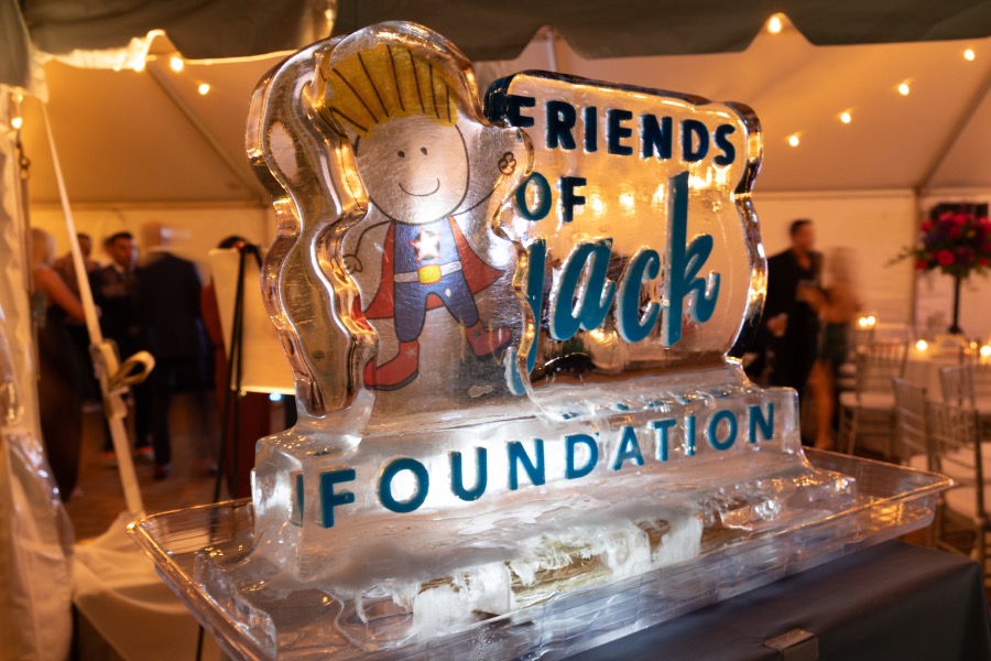 A carved ice sculpture of the Friends of Jack Foundation logo, lit up inside an event tent