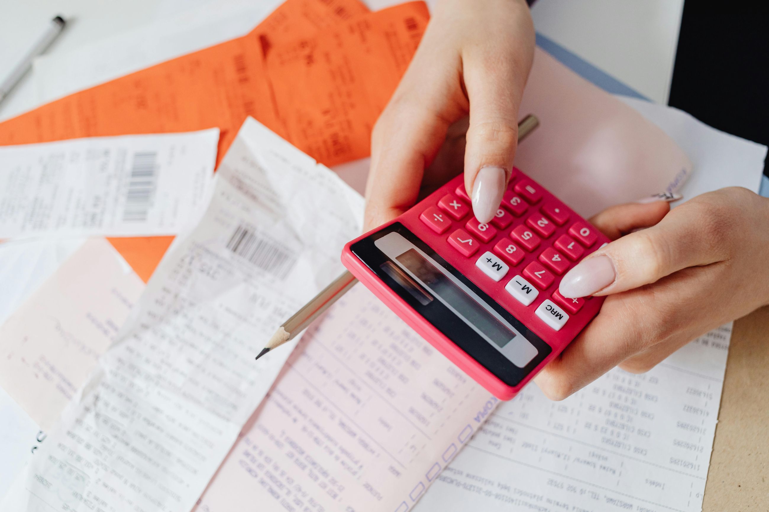 Person calculating medical expenses with receipts and bills, representing out-of-pocket costs for fertility benefits explained by EggFund.