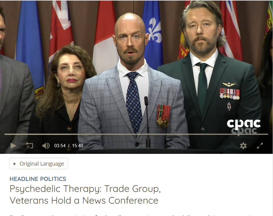 Smiling bearded man and young girl hiking on a forest trail with three people following behind.