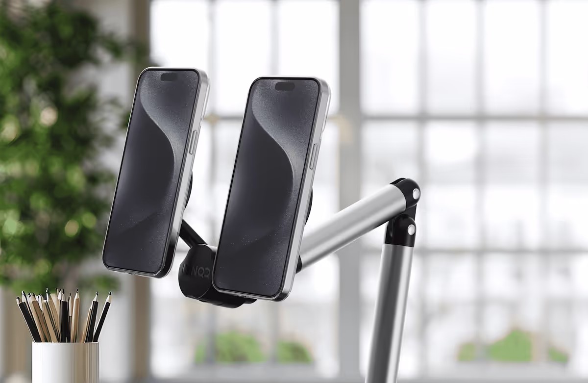 Two smartphones mounted on an adjustable metal arm near a pencil holder