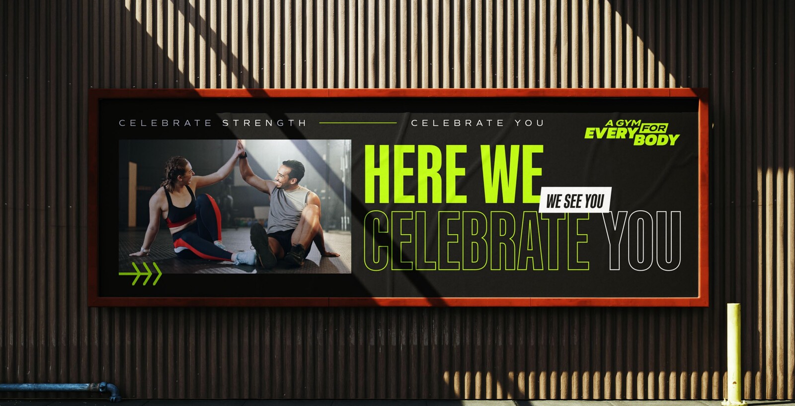 A Gym For Everybody billboard mockup, celebrate-strength creative on an exterior wall