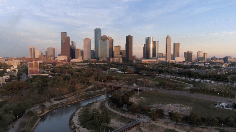 Looping aerial drone shot of downtown Houston at golden hour, opening moment of the Harris County Sports Authority impact film