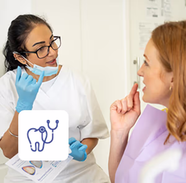 Dentist in white coat and blue gloves explaining dental care to a female patient.