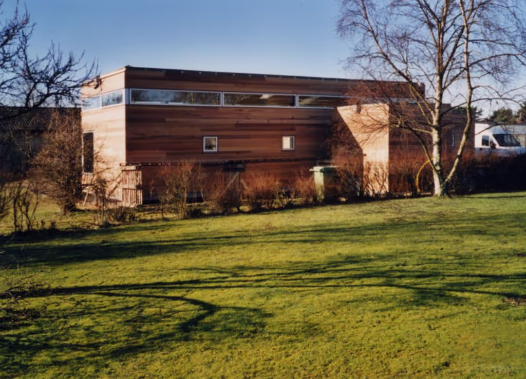 Foto av husets fasad och gröna trädgård.