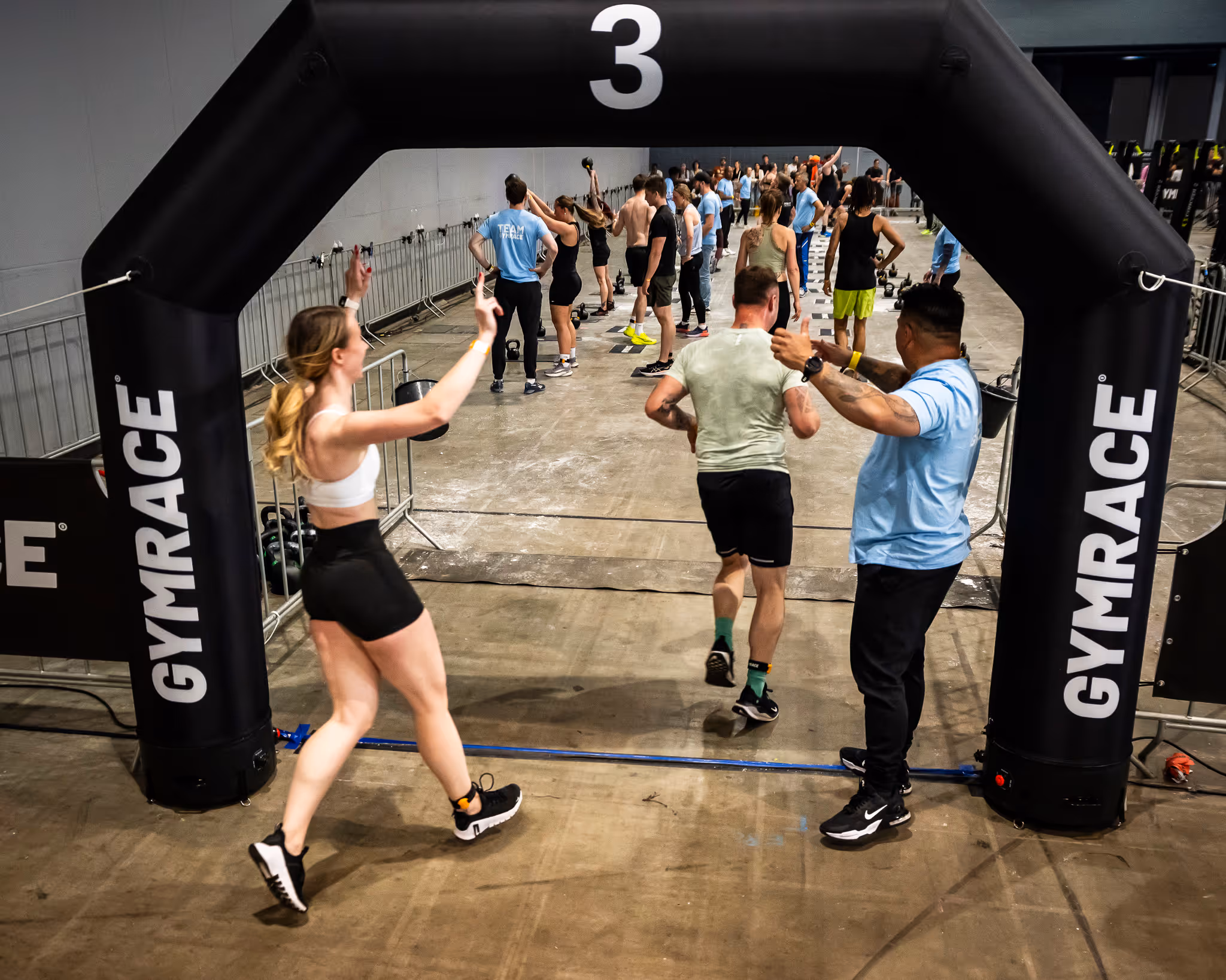 Participants passing under a GymRace arch during an indoor fitness competition.
