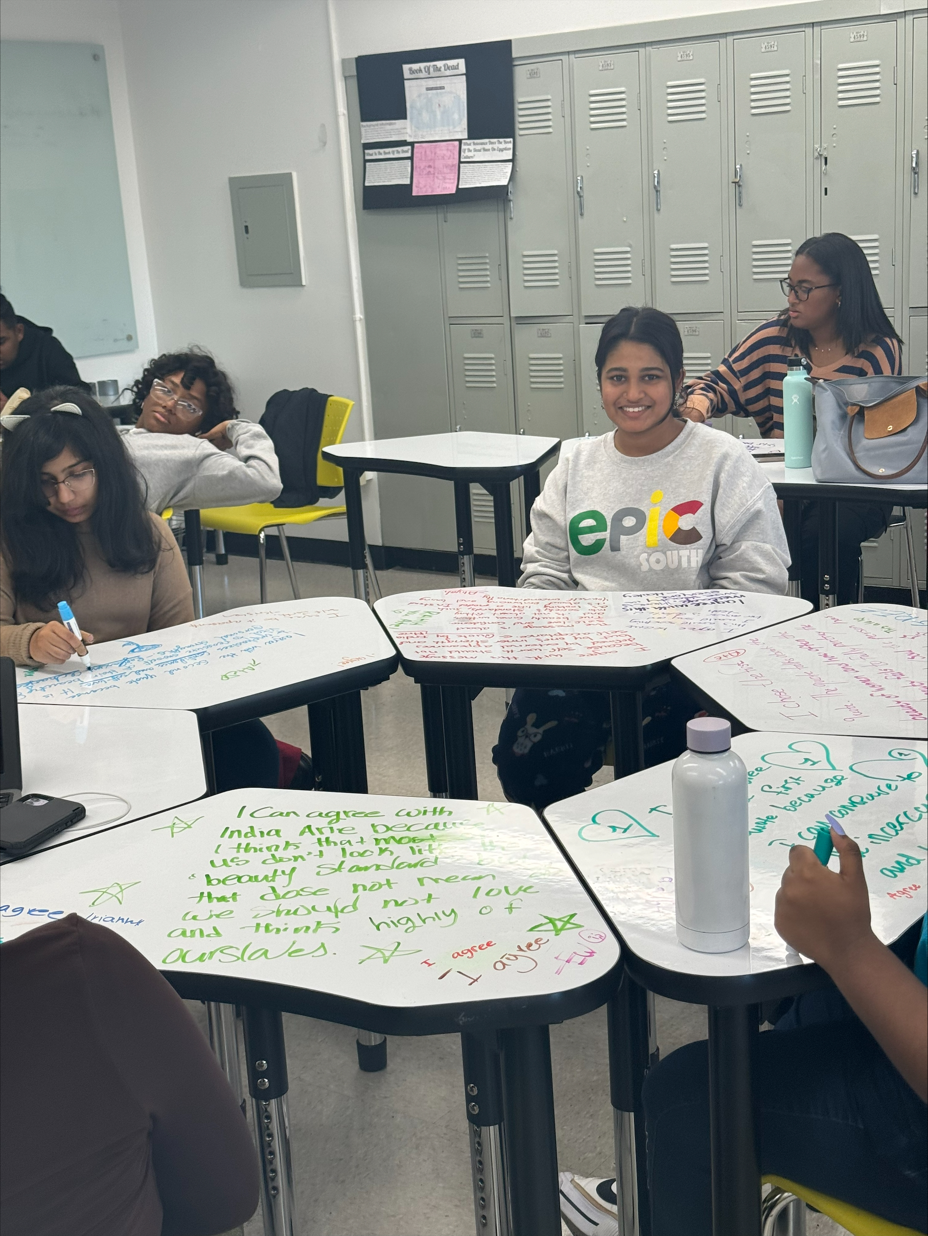 Students writing responses on whiteboard desks during collaborative classroom activity