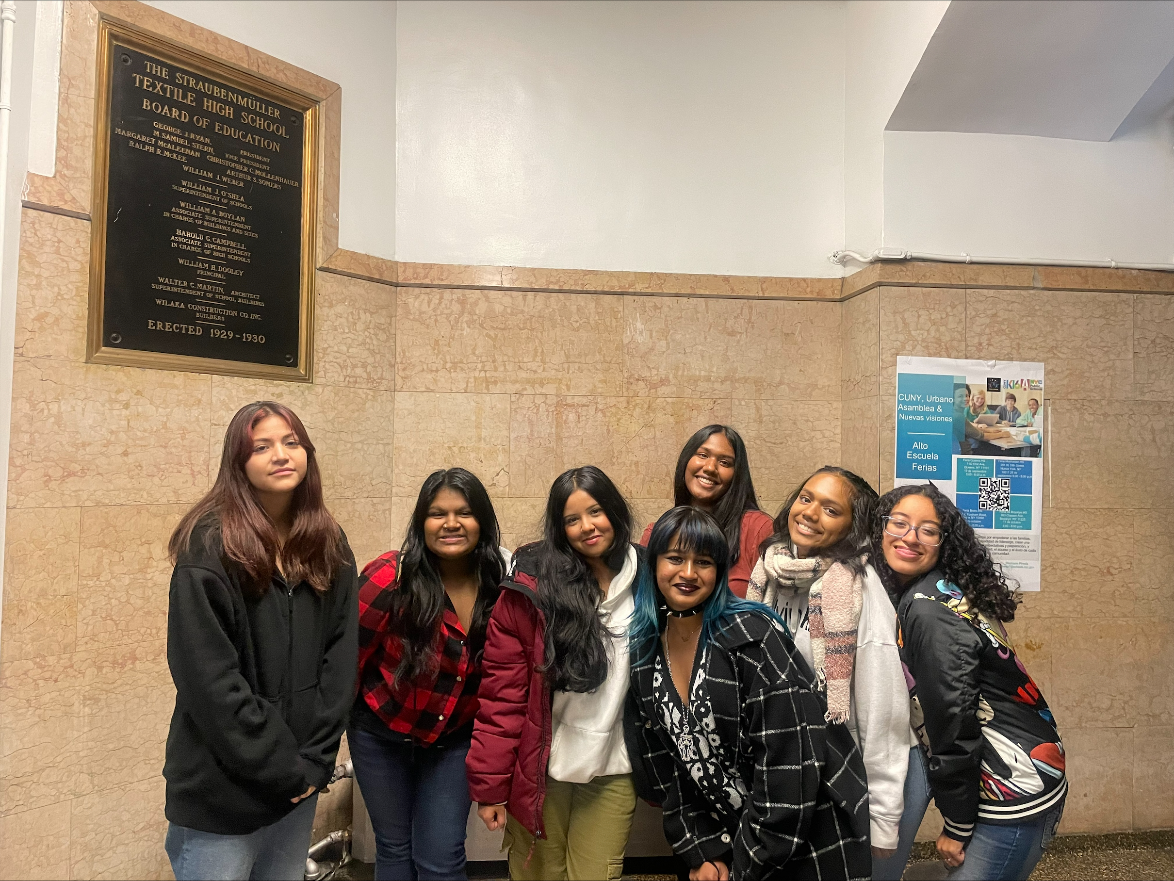 Seven students posing together inside Straubenmüller Textile High School lobby