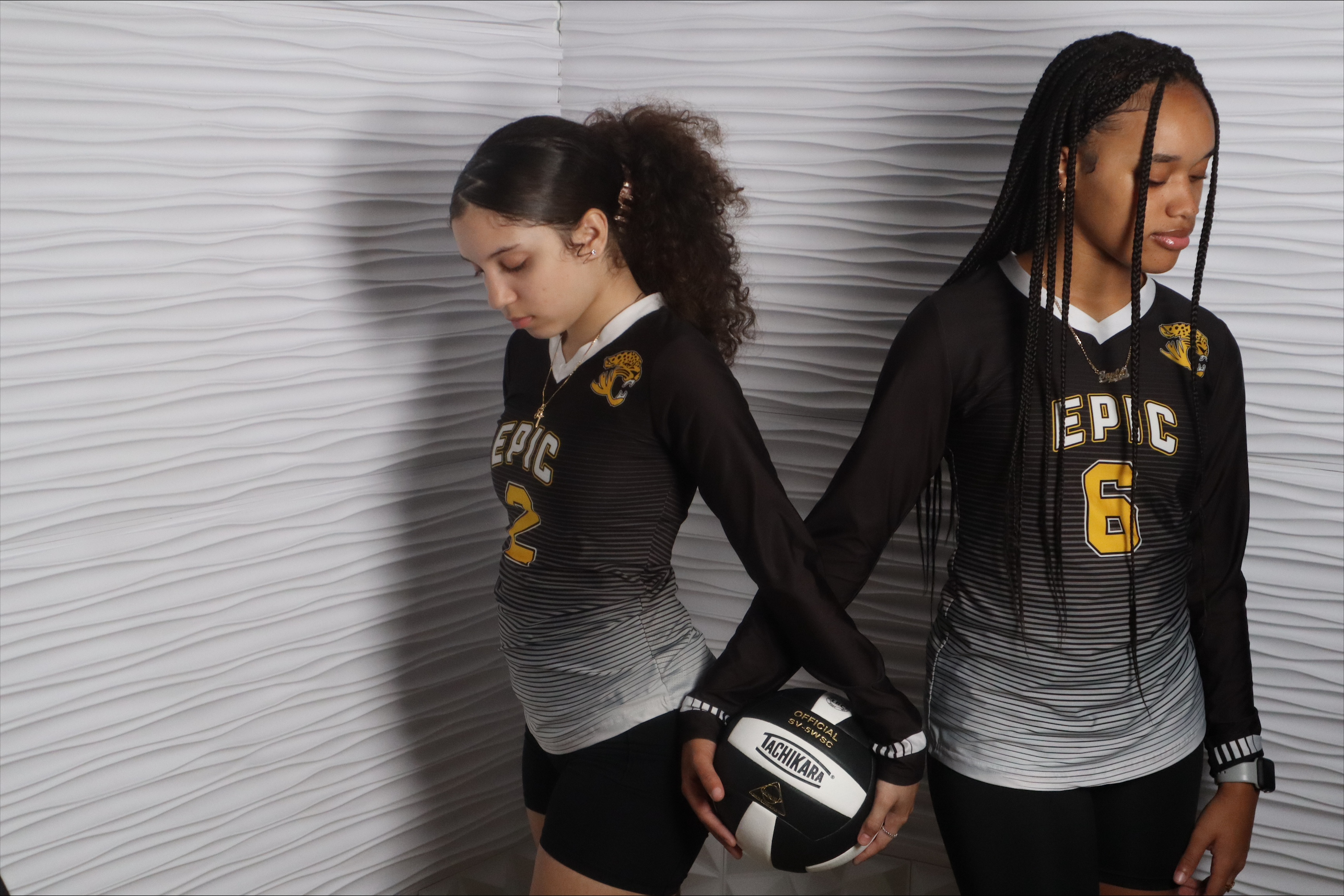 Two Epic volleyball players in black jerseys posing with a volleyball