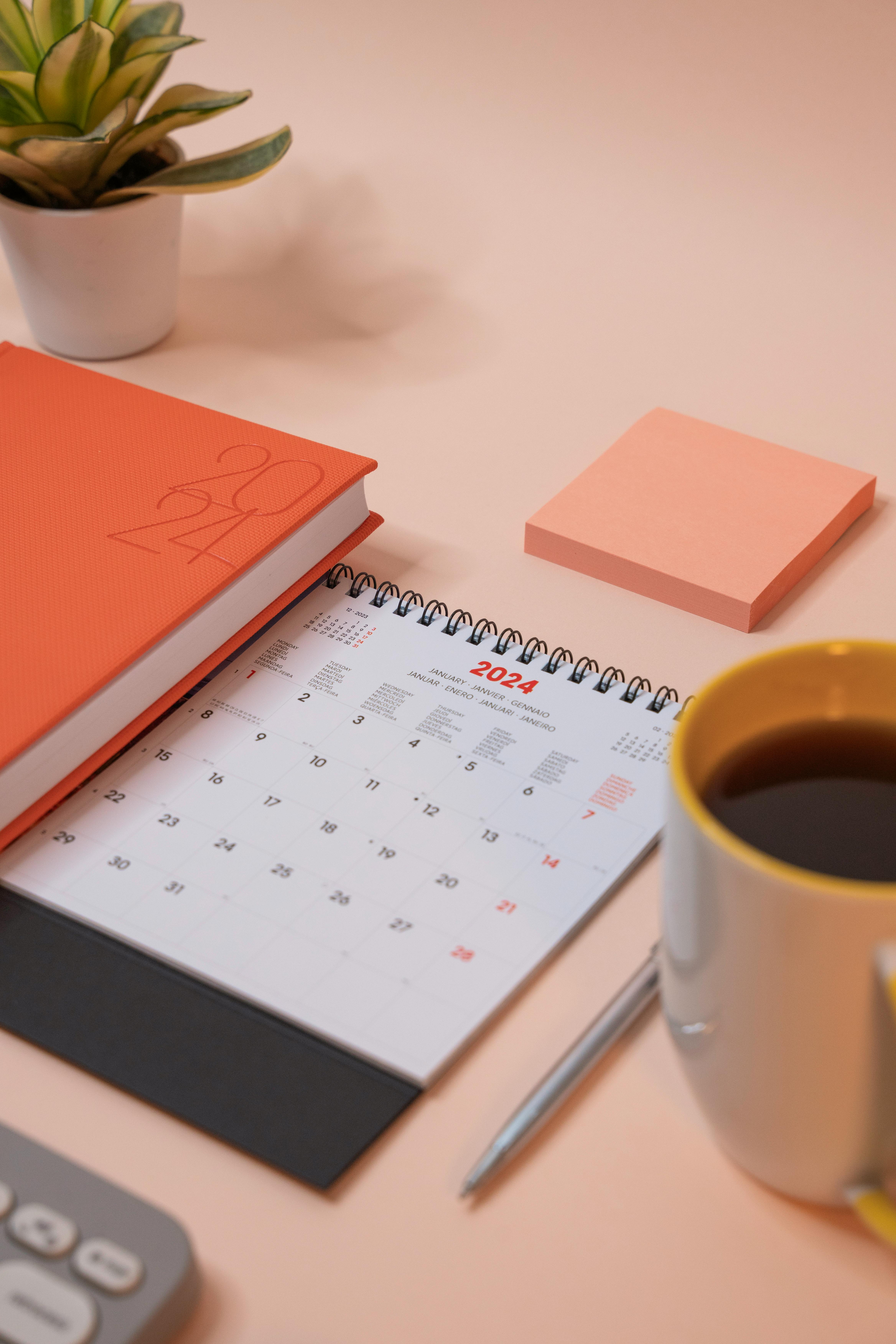 January 2024 desk calendar beside a planner and coffee mug