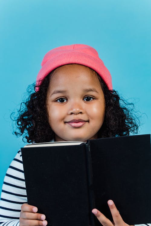 Young student smiling while holding an open book