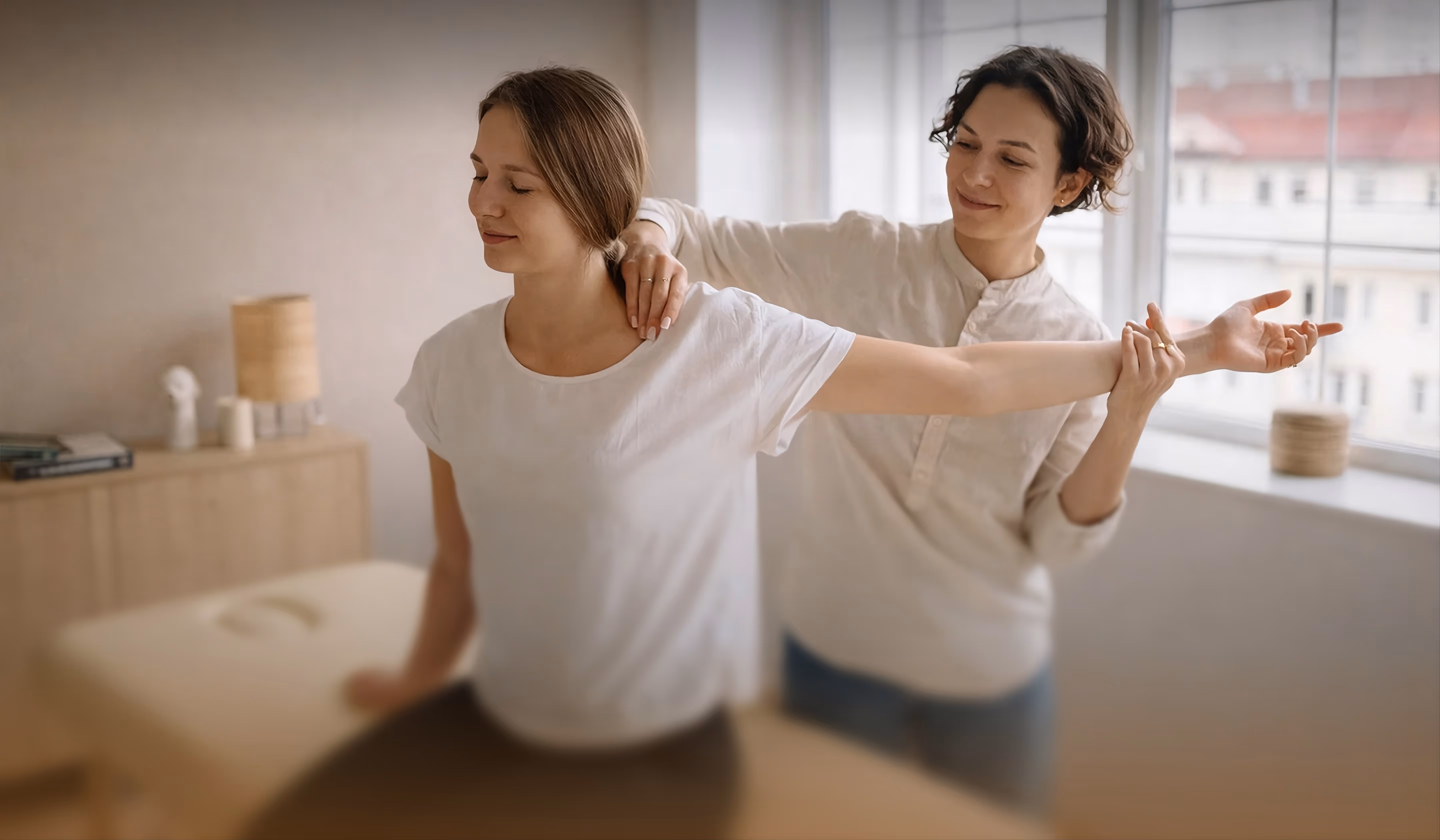 Physiotherapist assisting a woman in stretching her arm and shoulder during a therapy session.