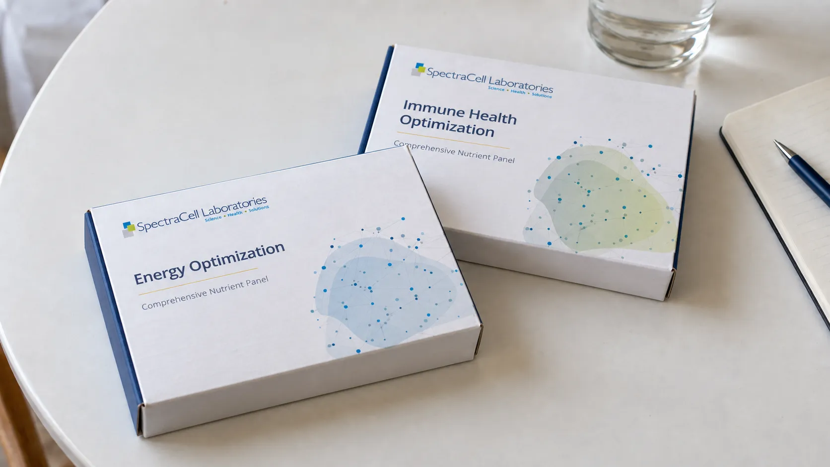 SpectraCell Energy Optimization and Immune Health Optimization test boxes on a table beside a notebook and water