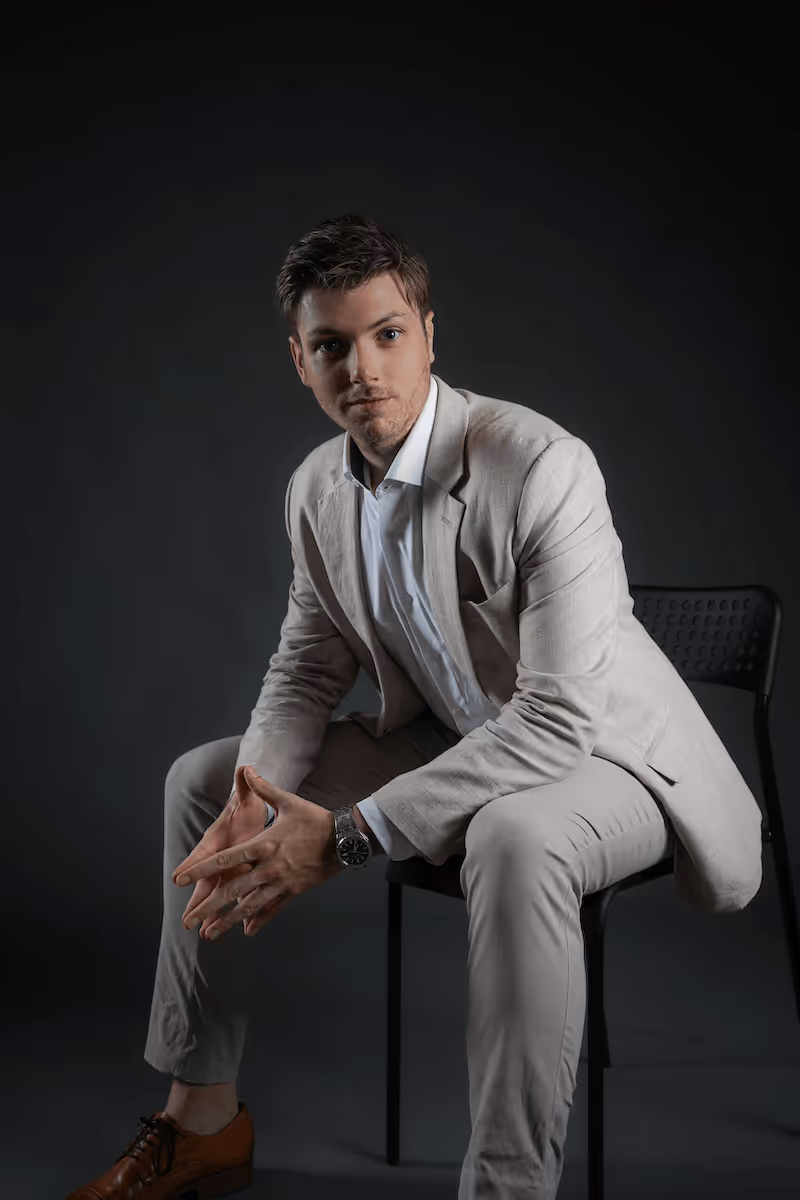 Full-body portrait of Julien Gadea, CEO of SalesMind AI, seated in a beige suit.