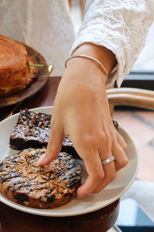 Assiette das laquelle se trouve deux parts de brownie et un cookie, avec une main qui essaye d’en prendre un morceau