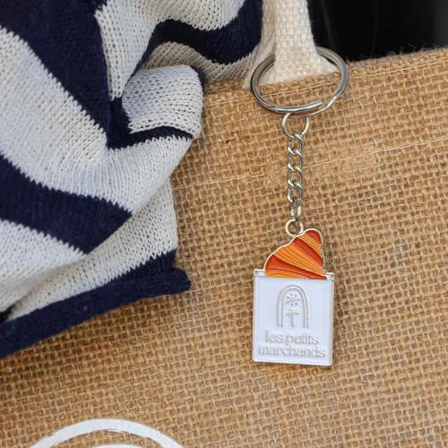 Zoom porte clé en forme de sachet avec un croissant, accroché à un sac en jute beige