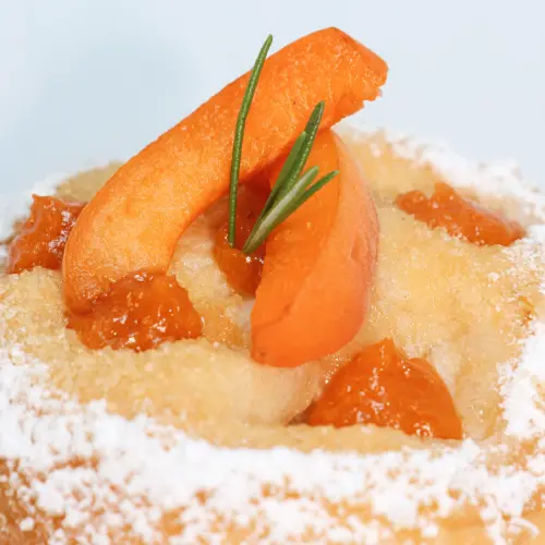 Zoom sur les morceaux d’abricot, et le romarin, posés sur une tarte au sucre, la viennoiserie du mois d’août