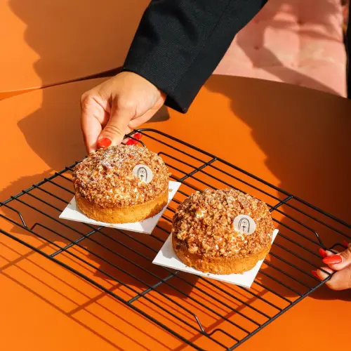 Deux tartelettes vanille pécan posées sur une grille dont une main qui en tient une 