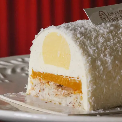 Zoom sur une part de bûche de Noël exotique à la noix de coco et fruit de la passion, avec les différentes couches