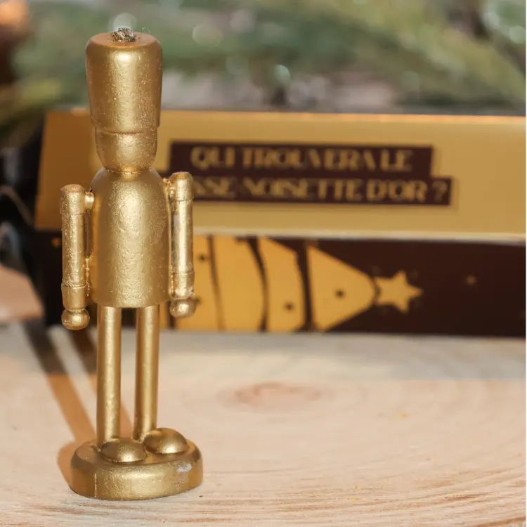 Zoom sur un casse noisette dorée et un crackers de Noël en fond 