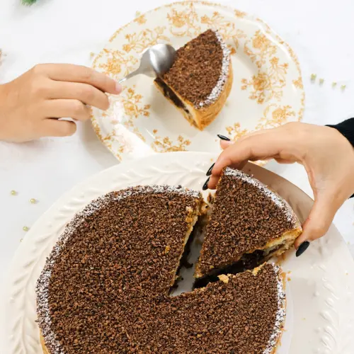 Galette des rois au chocolat avec une main qui prend une part 