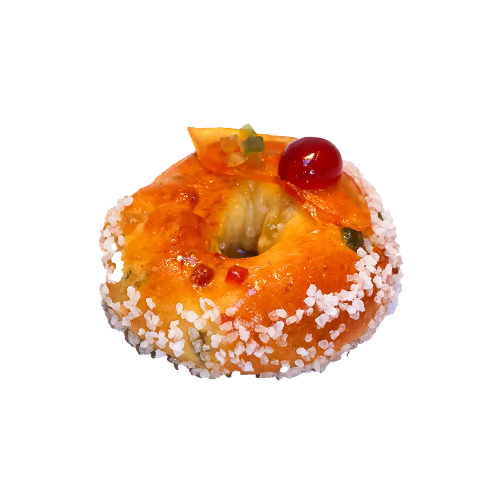 Une main prend une part de brioche “fruits confits” avec des morceaux de fruits confits et du sucre grain au-dessus