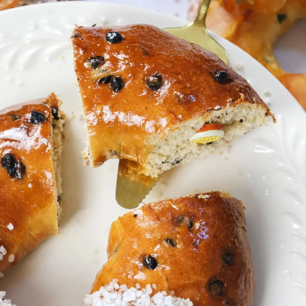 Zoom sur une part de brioche des rois "chocolat/orange" avec une fève qui dépasse de la part