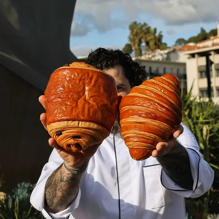 Le boulanger qui porte le croissant XL dans ses mains ainsi que le pain au chocolat XL