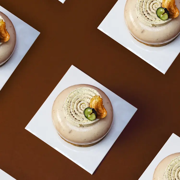 Répétition de plusieurs entremet marron et myrtille pris de haut sur fond marron