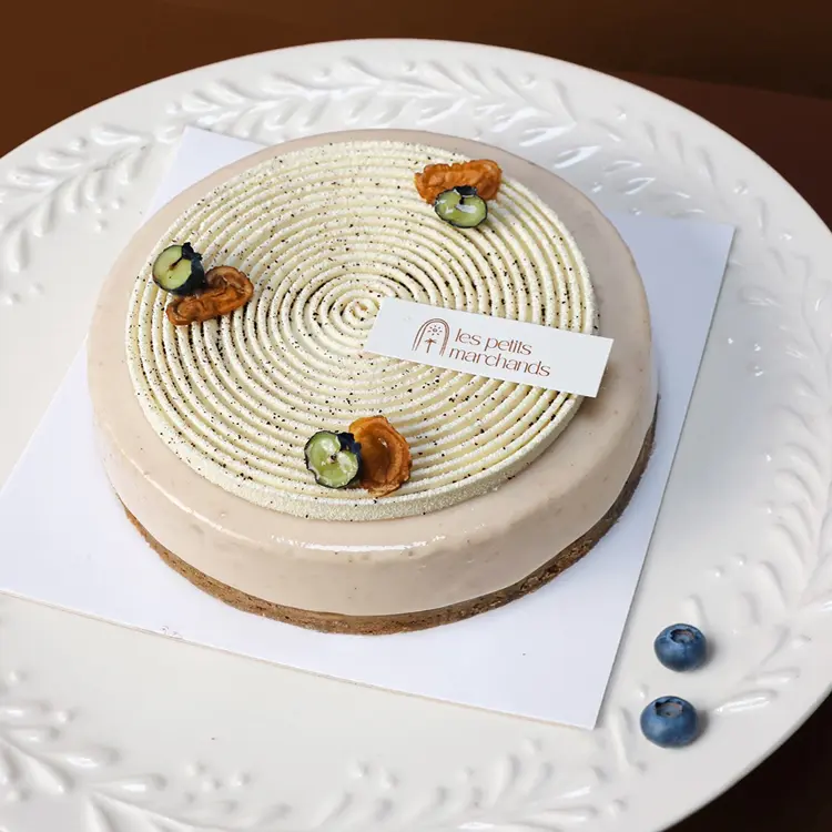 Entremet marron et myrtille pris de haut sur une assiette blanche, sur fond marron avec quelques myrtilles à côté
