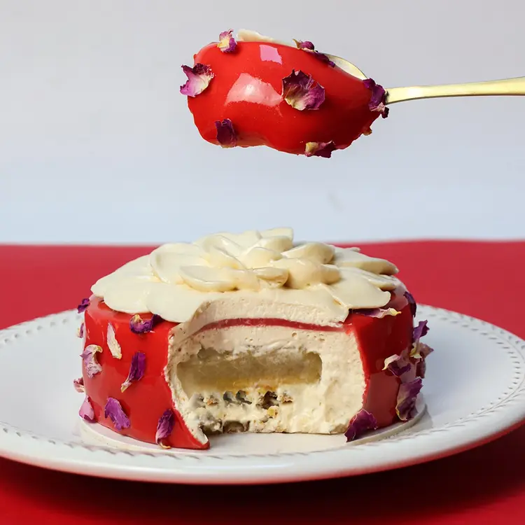 Zoom sur une cuillère qui a pris un généreux morceau de l'entremet, on voit apparaitre les couches de l'entremet (poire, caramel, vanille, graine de courge)