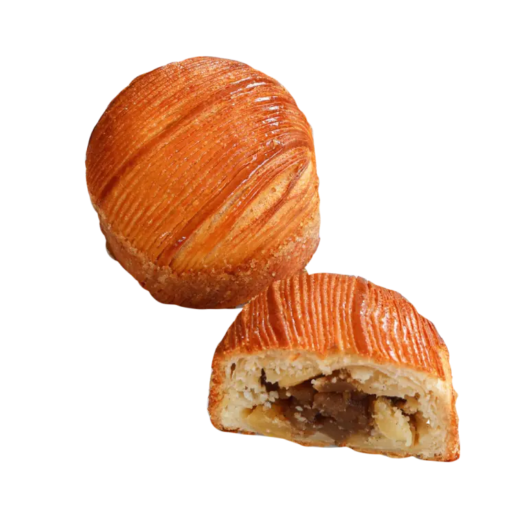 Un chausson aux pommes entier et une moitié de chausson à côté laissant apparaitre le fourrage aux pommes caramélisées