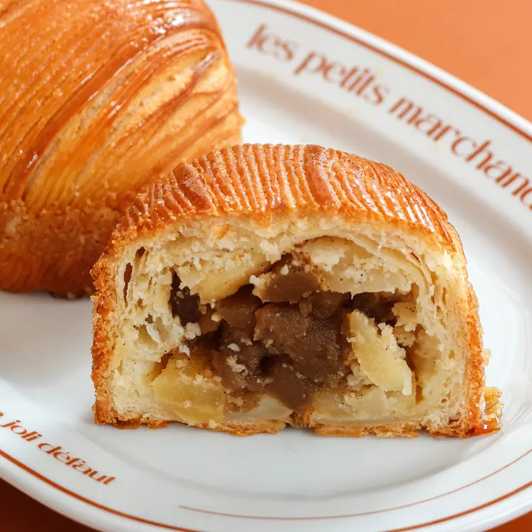 Zoom sur une moitié de chausson aux pommes laissant apparaitre des pommes caramélisées à l'intérieur