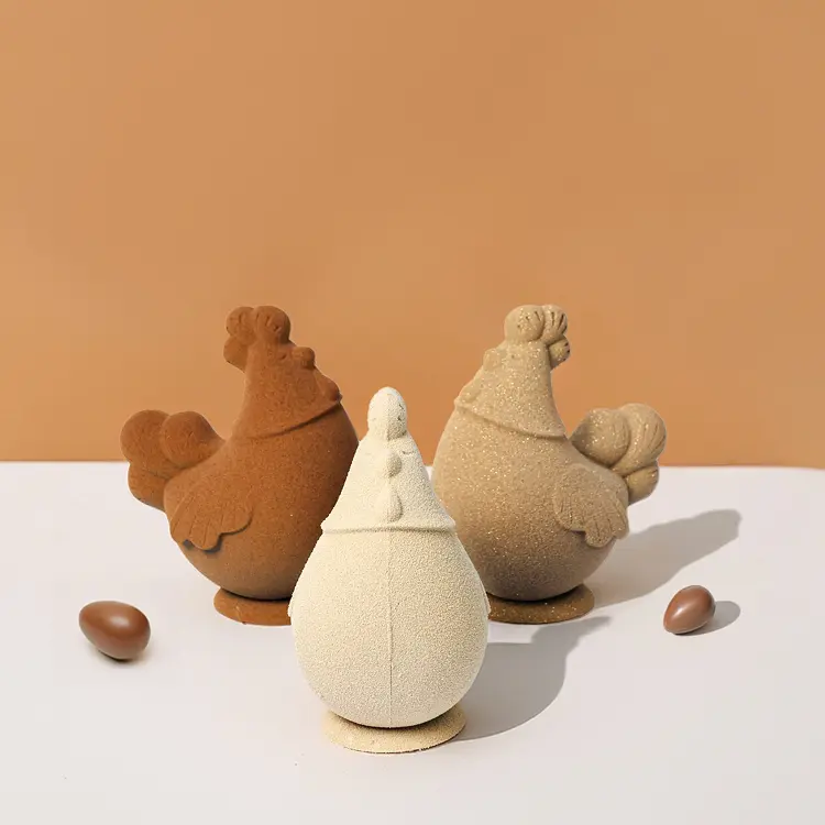 Trois poules en chocolat (blond, noir et lait) en ronde avec un petit oeuf en chocolat derrière elles