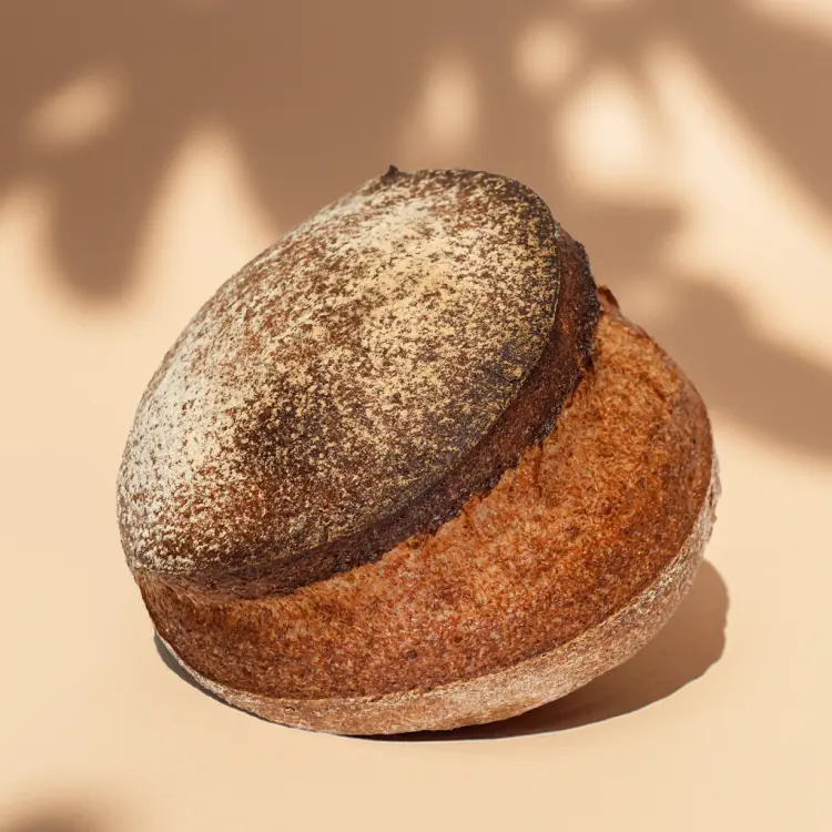 Un pain complet sur fond beige avec quelques ombres derrière