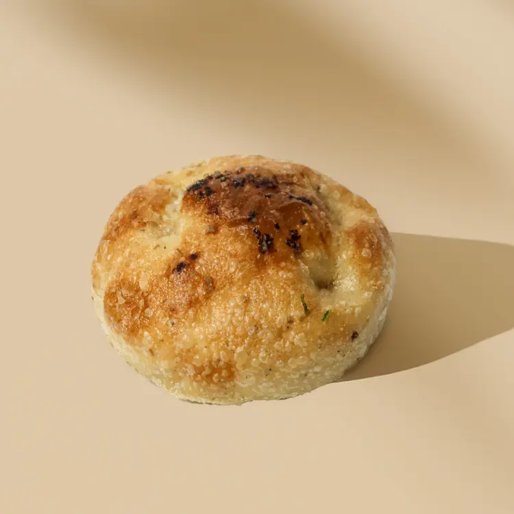 Une focaccia individuelle sur fond beige avec quelques ombres derrière