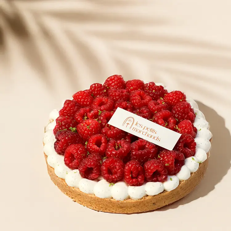 Notre tarte framboise pour 4/6 personnes sur fond beige avec quelques ombres autour