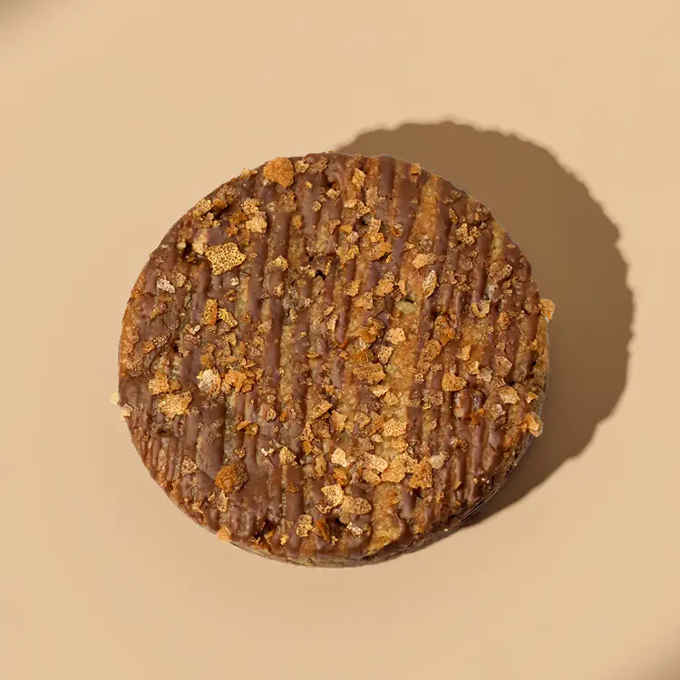 Le cookie chocolat au lait et noix de pécan sur fond beige avec des ombres autour