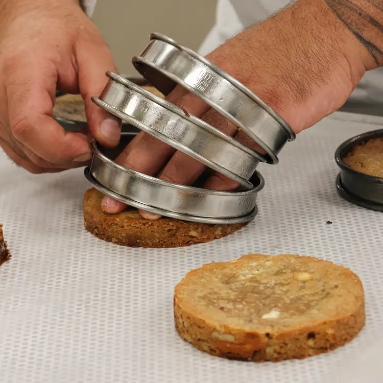 Backstage de préparation du cookie pécan dans le labo de production, une main de pâtissier démoule des cookies