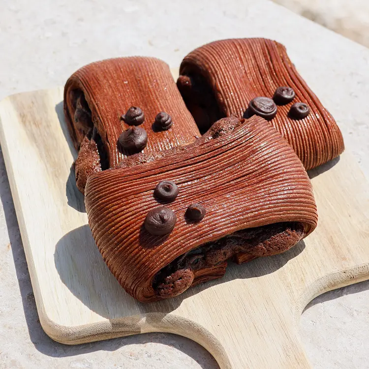 Trois pains suisse au brownie posés sur une planche en bois