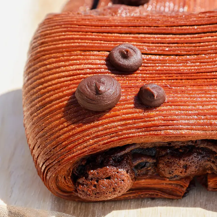 Zoom sur les détails du pain suisse brownie avec le brownie qui dégouline devant, et trois petits points de brownie sur le dessus