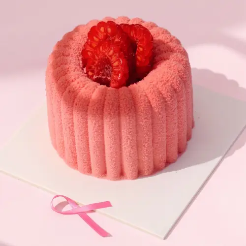 Zoom sur notre entremet vanille fruits rouges pour octobre rose sur fond rose avec un ruban rose posé à côté du produit
