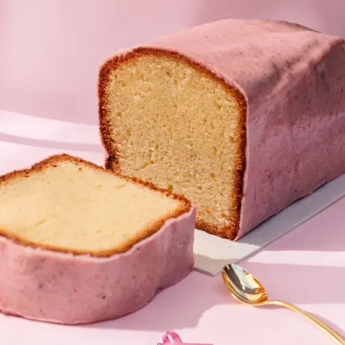 Zoom sur une part de cake au citron recouvert d'un glaçage au chocolat blanc et à la framboise 