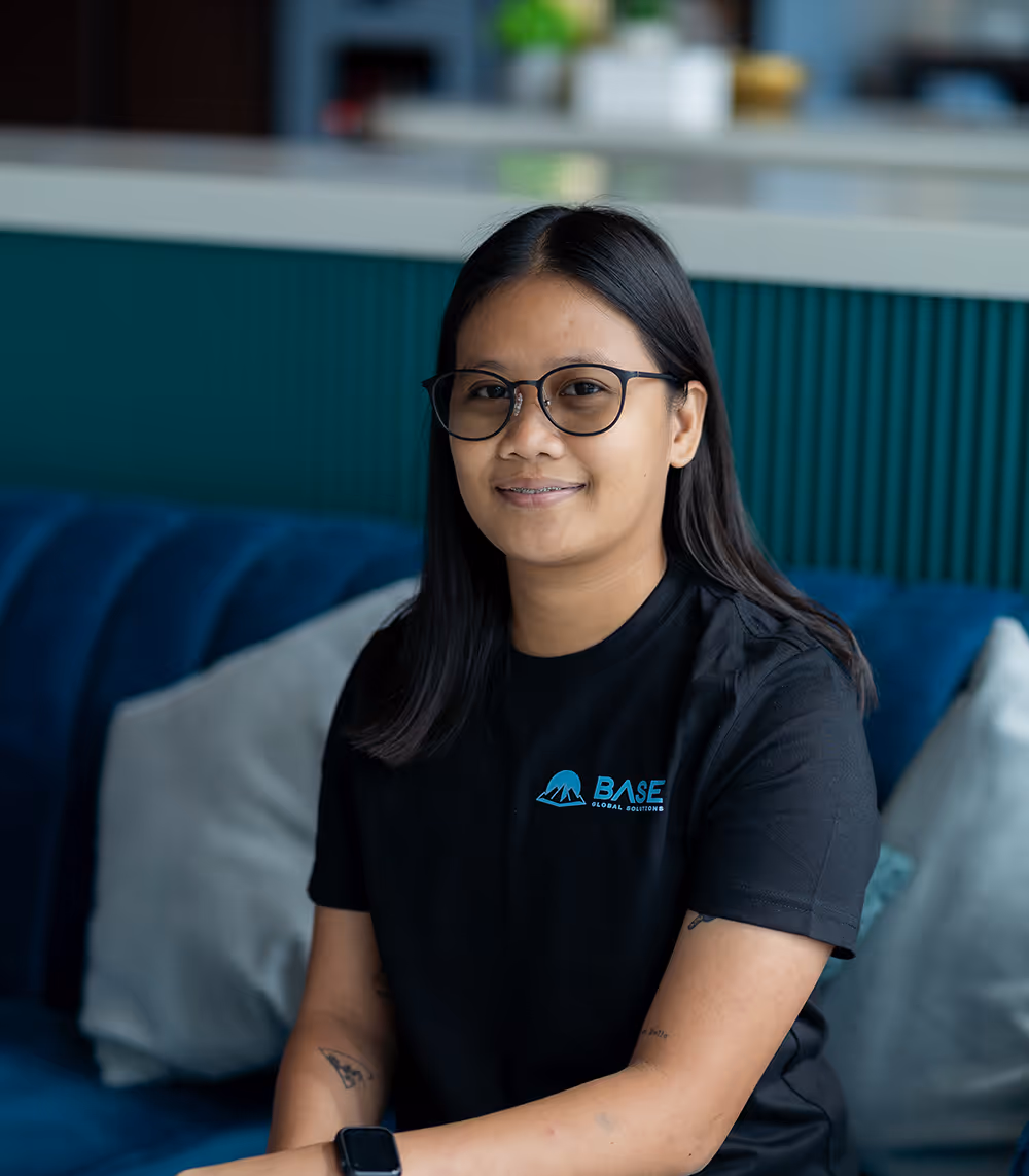 Smiling woman wearing glasses and a base global t-shirt looking at the camera