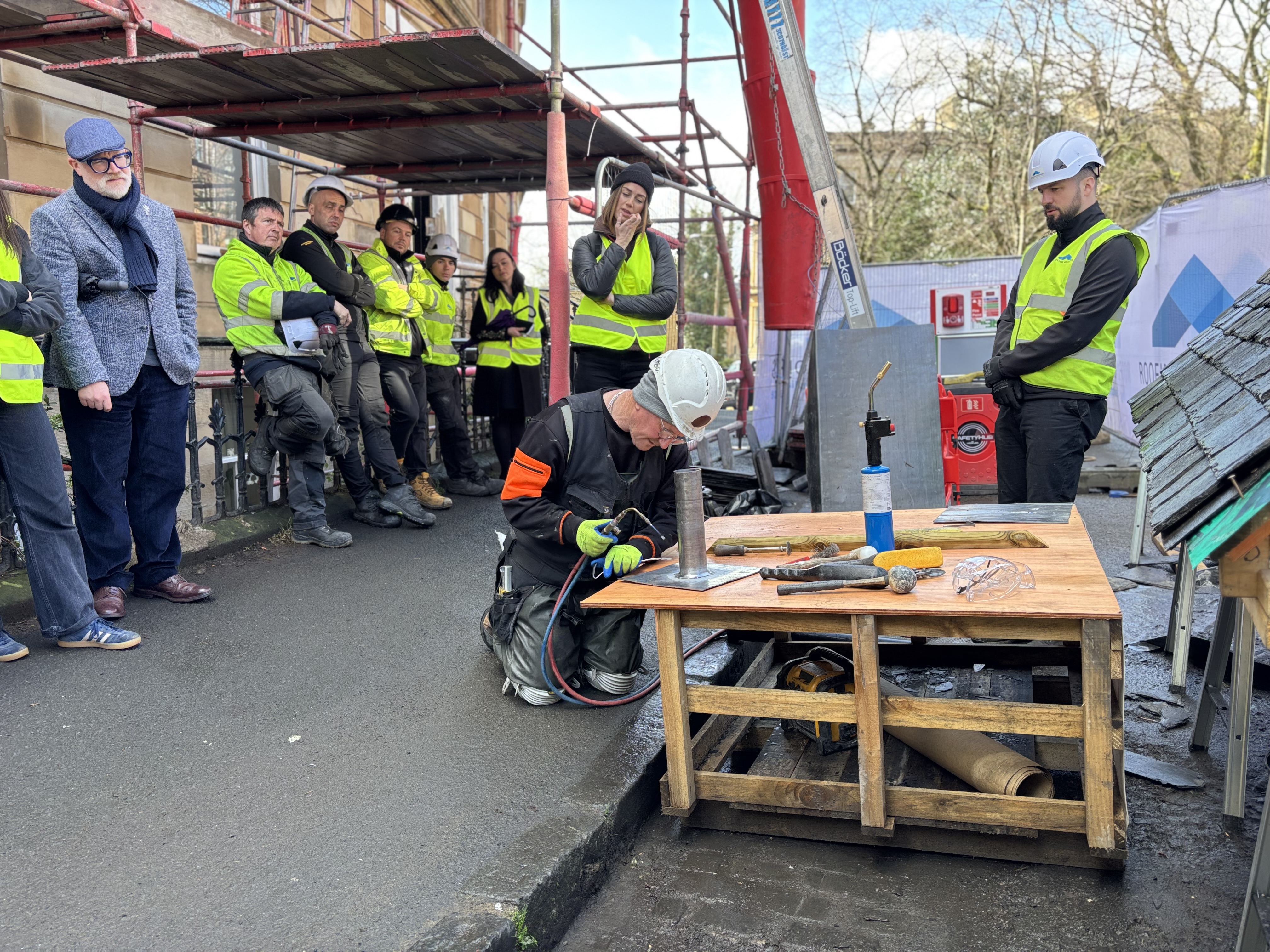 Leadwork demonstration at a Roofing Advisors heritage roofing demo day, showing traditional lead pipe sleeve installation techniques